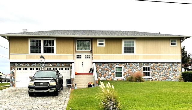 5111 Bay State Rd, Palmetto, FL 34221 - view of front of home with decorative driveway, a front lawn, stone siding, an attached garage, and a shingled roof