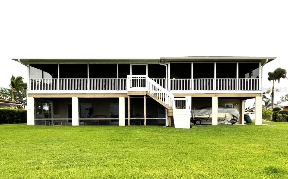 5111 Bay State Rd, Palmetto, FL 34221 - back of property with a sunroom, a lawn, and stairway
