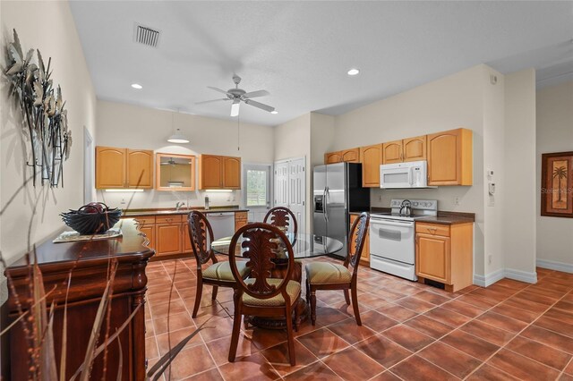 7025 Saddle Creek Cir, Sarasota, FL 34241 - kitchen featuring white appliances, dark countertops, dark tile patterned floors, light brown cabinets, and ceiling fan