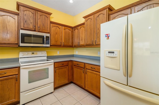 5609 Spanish Point Ct, Palmetto, FL 34221 - kitchen featuring white appliances, light tile patterned floors, and brown cabinetry