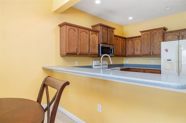 5609 Spanish Point Ct, Palmetto, FL 34221 - kitchen with stainless steel microwave, white refrigerator with ice dispenser, stove, a peninsula, and light tile patterned flooring
