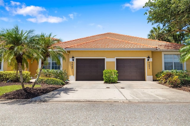 5609 Spanish Point Ct, Palmetto, FL 34221 - view of front of house featuring a garage, concrete driveway, stucco siding, and a tile roof