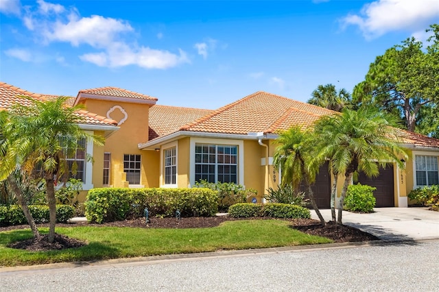 5609 Spanish Point Ct, Palmetto, FL 34221 - mediterranean / spanish-style house with an attached garage, driveway, a tiled roof, and stucco siding