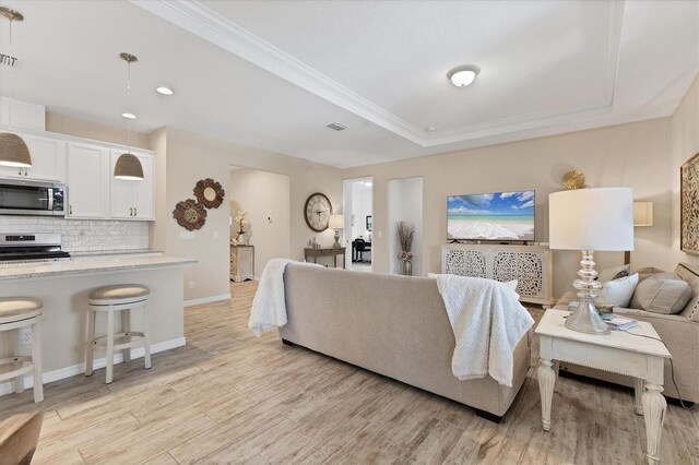 4524 Baltry Ct, Bradenton, FL 34211 - living room with light wood-style floors, a tray ceiling, baseboards, recessed lighting, and ornamental molding