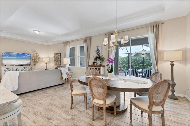 4524 Baltry Ct, Bradenton, FL 34211 - dining room featuring light wood-style floors, a chandelier, crown molding, a tray ceiling, and baseboards