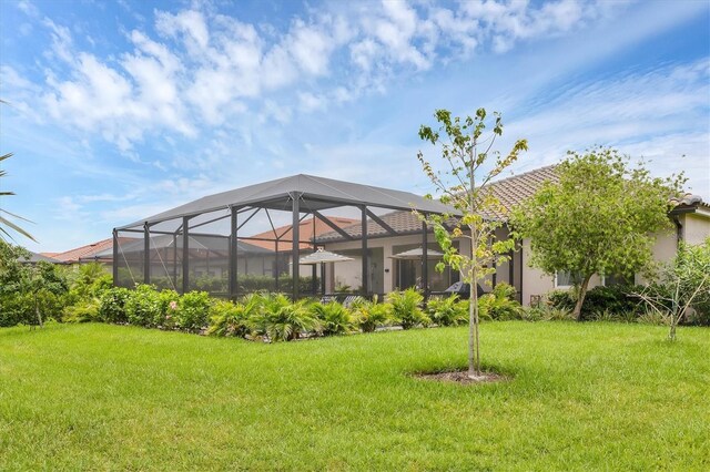 4524 Baltry Ct, Bradenton, FL 34211 - rear view of house featuring a lawn, glass enclosure, stucco siding, and a tiled roof