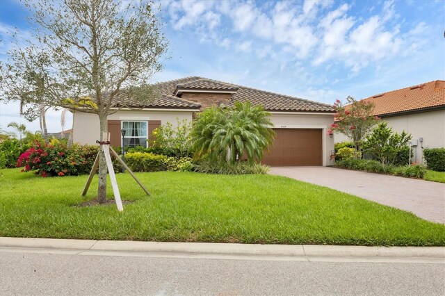4524 Baltry Ct, Bradenton, FL 34211 - mediterranean / spanish-style home with an attached garage, concrete driveway, a tile roof, a front lawn, and stucco siding