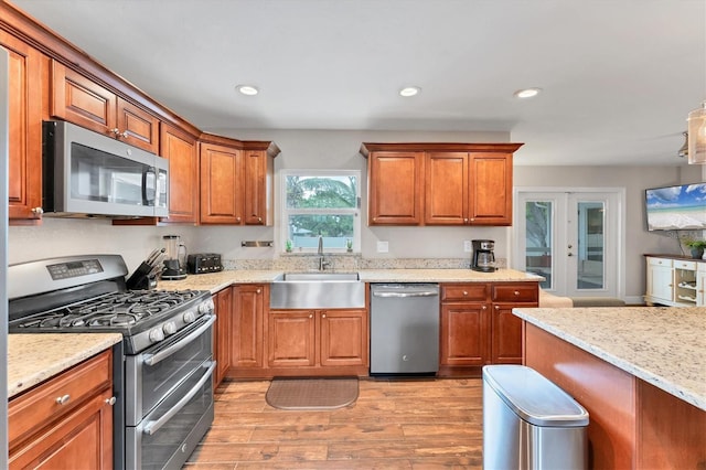 7727 9th Avenue Dr NW, Bradenton, FL 34209 - kitchen featuring stainless steel appliances, a sink, light wood-style floors, brown cabinets, and recessed lighting