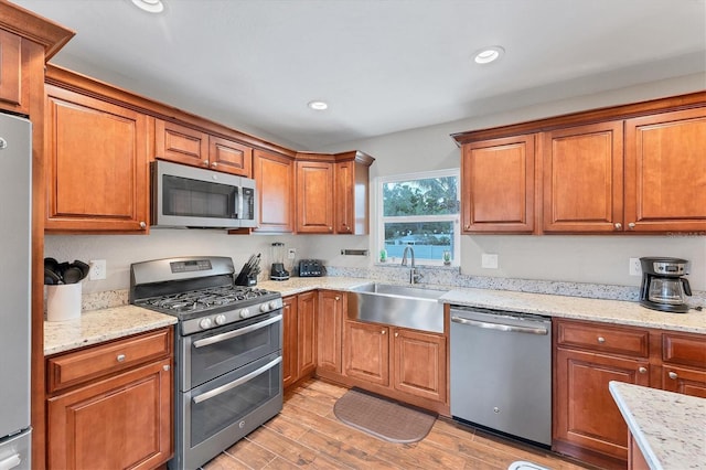 7727 9th Avenue Dr NW, Bradenton, FL 34209 - kitchen with appliances with stainless steel finishes, a sink, light wood-type flooring, brown cabinetry, and recessed lighting