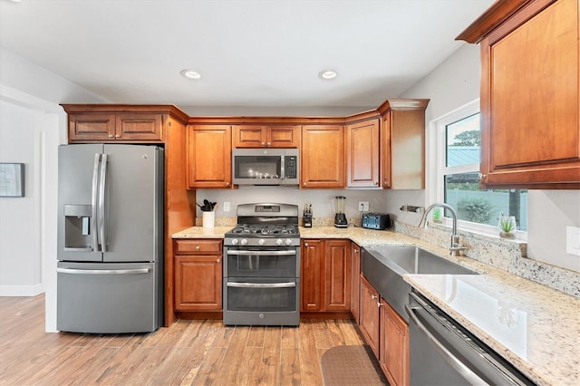 7727 9th Avenue Dr NW, Bradenton, FL 34209 - kitchen featuring stainless steel appliances, light wood-style flooring, a sink, brown cabinetry, and recessed lighting