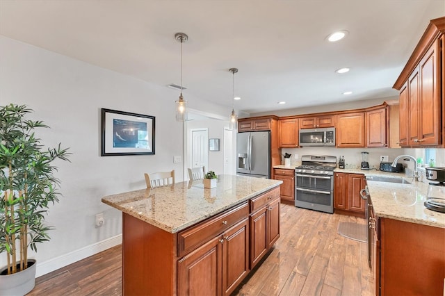 7727 9th Avenue Dr NW, Bradenton, FL 34209 - kitchen featuring stainless steel appliances, a sink, light wood-style floors, brown cabinets, and light stone countertops