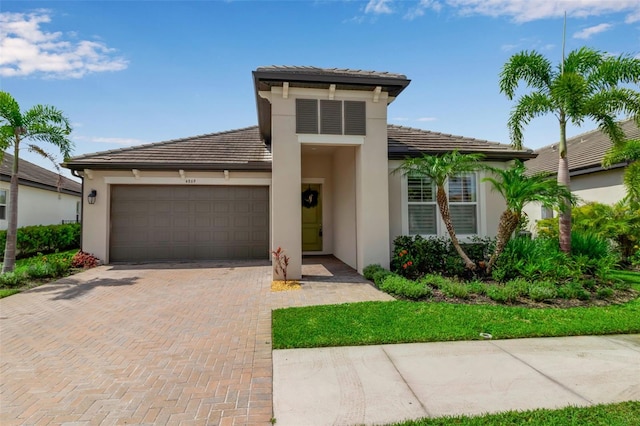 4869 Antrim Dr, Sarasota, FL 34240 - view of front facade with an attached garage, stucco siding, decorative driveway, and a tiled roof