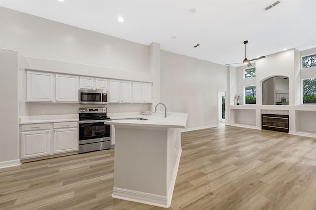 5103 Twin Creeks Dr, Valrico, FL 33596 - kitchen with stainless steel appliances, light countertops, a towering ceiling, white cabinetry, and a tiled fireplace