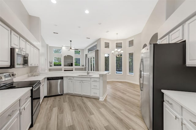5103 Twin Creeks Dr, Valrico, FL 33596 - kitchen featuring stainless steel appliances, a peninsula, a chandelier, light countertops, and light wood finished floors