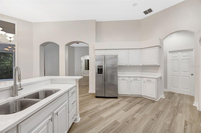 5103 Twin Creeks Dr, Valrico, FL 33596 - kitchen with stainless steel fridge with ice dispenser, arched walkways, light countertops, white cabinets, and light wood-type flooring
