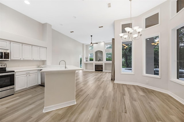 5103 Twin Creeks Dr, Valrico, FL 33596 - kitchen featuring appliances with stainless steel finishes, high vaulted ceiling, light wood-style flooring, light countertops, and a chandelier