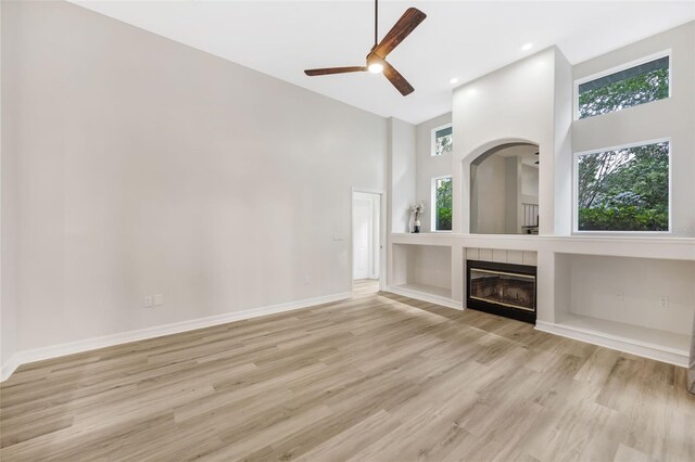 5103 Twin Creeks Dr, Valrico, FL 33596 - unfurnished living room with a towering ceiling, a fireplace, ceiling fan, light wood-style flooring, and recessed lighting