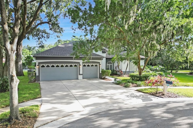 5103 Twin Creeks Dr, Valrico, FL 33596 - view of front of home featuring an attached garage, driveway, stucco siding, a shingled roof, and a front lawn