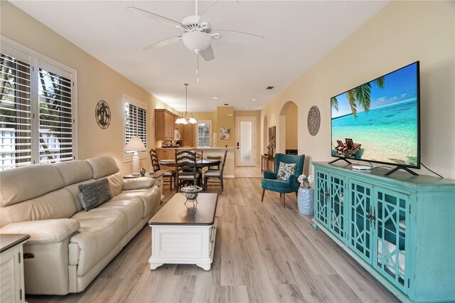8579 54th Avenue Cir E, Bradenton, FL 34211 - living area featuring light wood finished floors, a ceiling fan, arched walkways, and a chandelier