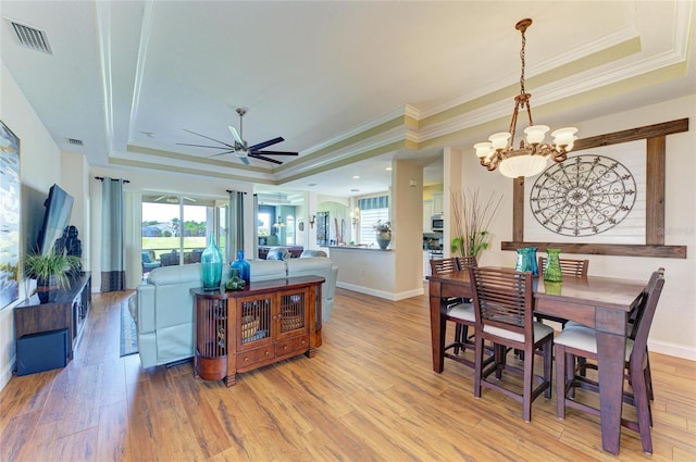8906 Stone Harbour Loop, Bradenton, FL 34212 - dining room with a tray ceiling, a chandelier, ornamental molding, a ceiling fan, and light wood-style flooring