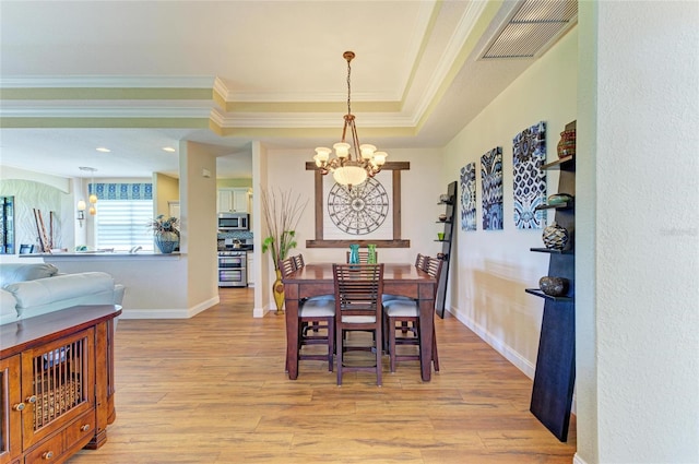 8906 Stone Harbour Loop, Bradenton, FL 34212 - dining area featuring a chandelier, light wood-style flooring, ornamental molding, and a tray ceiling