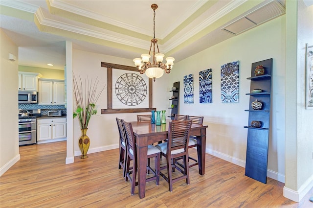 8906 Stone Harbour Loop, Bradenton, FL 34212 - dining room featuring a chandelier, ornamental molding, light wood-style flooring, and a raised ceiling