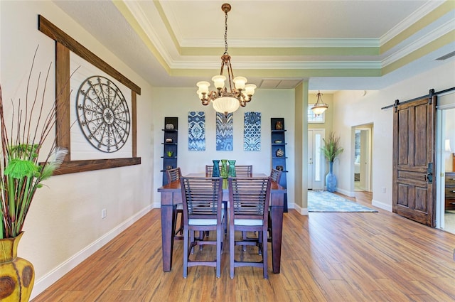 8906 Stone Harbour Loop, Bradenton, FL 34212 - dining area with a chandelier, a raised ceiling, a barn door, wood finished floors, and crown molding