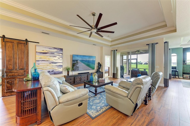 8906 Stone Harbour Loop, Bradenton, FL 34212 - living room featuring a tray ceiling, ceiling fan, a barn door, light wood finished floors, and ornamental molding