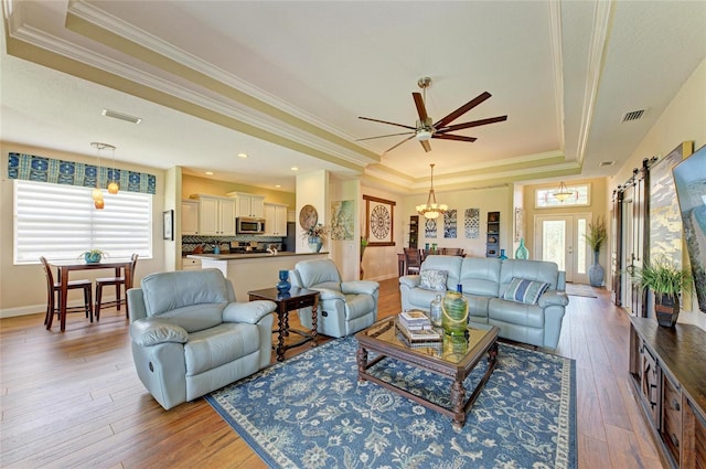 8906 Stone Harbour Loop, Bradenton, FL 34212 - living room with a raised ceiling, ornamental molding, light wood-type flooring, ceiling fan, and a chandelier