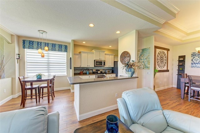 8906 Stone Harbour Loop, Bradenton, FL 34212 - kitchen with appliances with stainless steel finishes, dark countertops, open floor plan, light wood finished floors, and crown molding