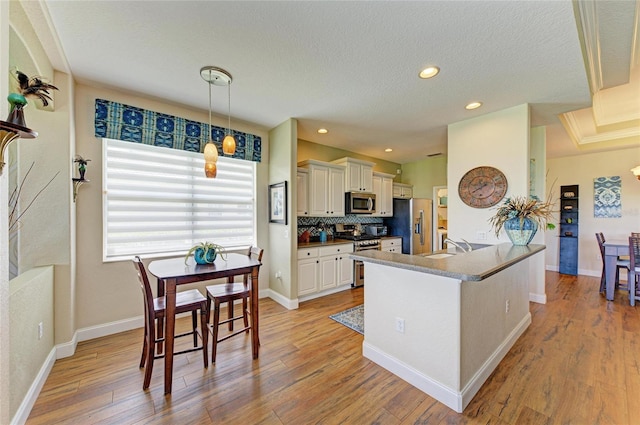 8906 Stone Harbour Loop, Bradenton, FL 34212 - kitchen with stainless steel appliances, a textured ceiling, light wood-style flooring, backsplash, and a peninsula