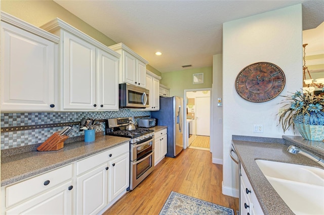 8906 Stone Harbour Loop, Bradenton, FL 34212 - kitchen featuring appliances with stainless steel finishes, light wood-style floors, decorative backsplash, white cabinetry, and recessed lighting