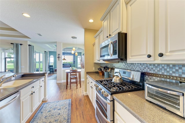 8906 Stone Harbour Loop, Bradenton, FL 34212 - kitchen with stainless steel appliances, backsplash, light wood-style flooring, recessed lighting, and decorative light fixtures
