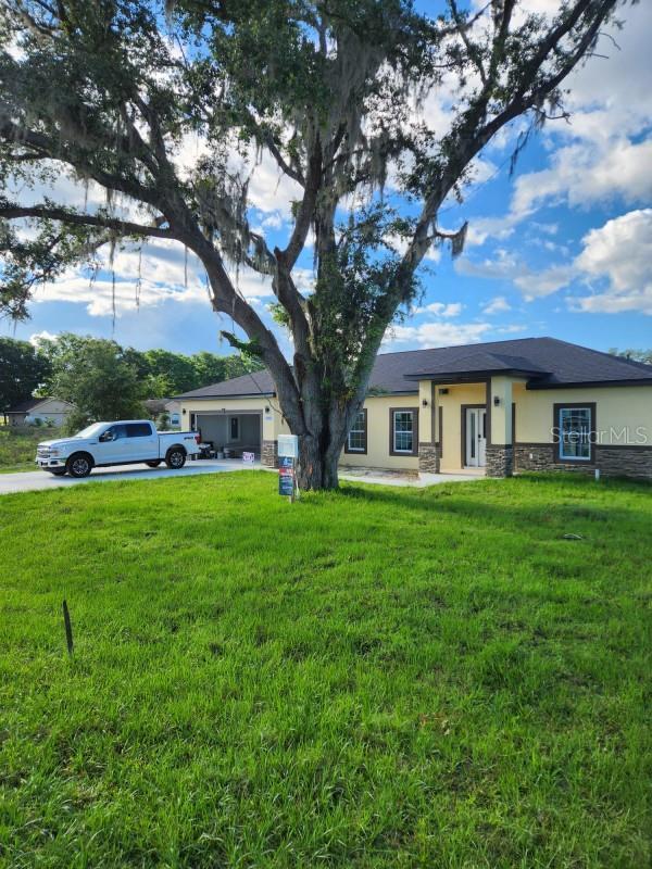 13074 SW 104th Ln, Dunnellon, FL 34432 - view of front facade featuring stone siding, stucco siding, and a front lawn