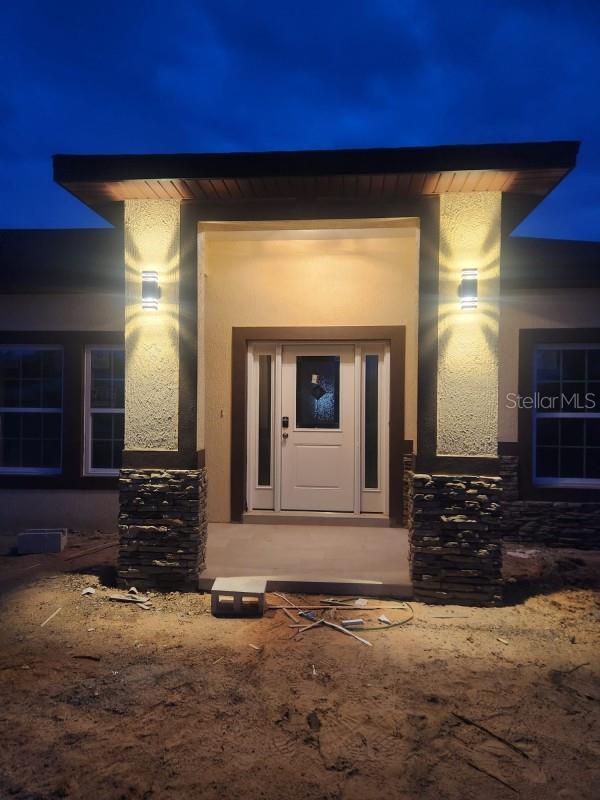 13074 SW 104th Ln, Dunnellon, FL 34432 - exterior entry at twilight with stone siding and stucco siding