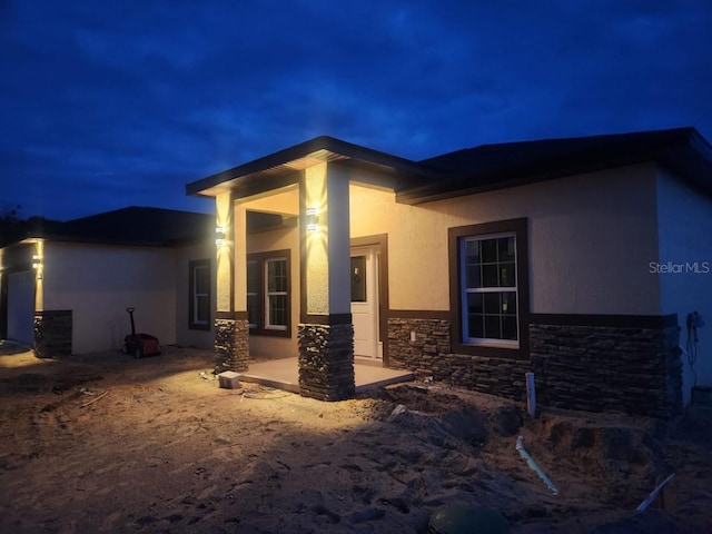 13074 SW 104th Ln, Dunnellon, FL 34432 - property exterior at twilight with stone siding, stucco siding, and a patio area