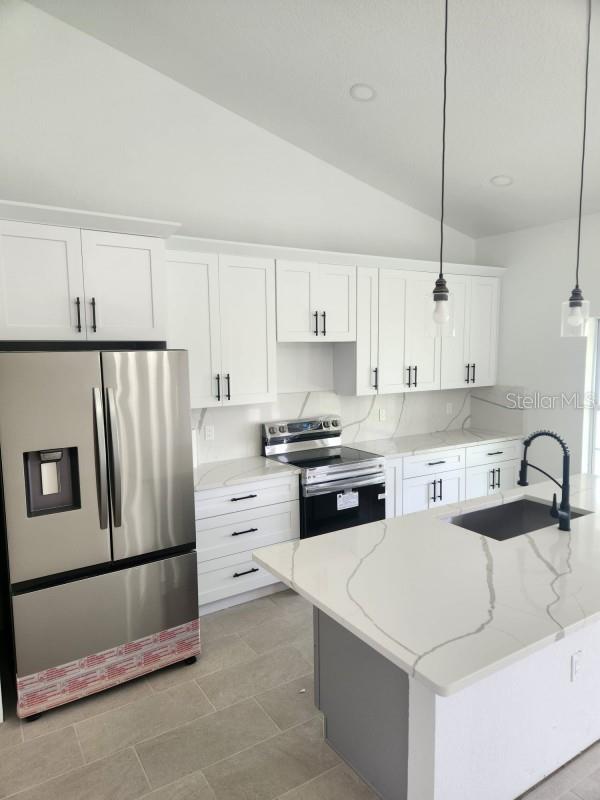 13074 SW 104th Ln, Dunnellon, FL 34432 - kitchen featuring appliances with stainless steel finishes, a sink, white cabinetry, lofted ceiling, and pendant lighting