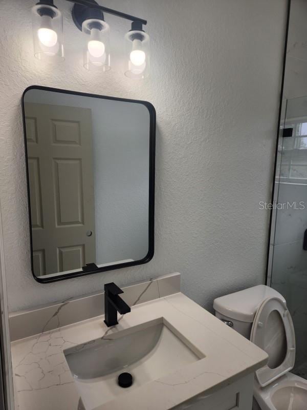 13074 SW 104th Ln, Dunnellon, FL 34432 - bathroom featuring a textured wall, vanity, toilet, and a shower with door