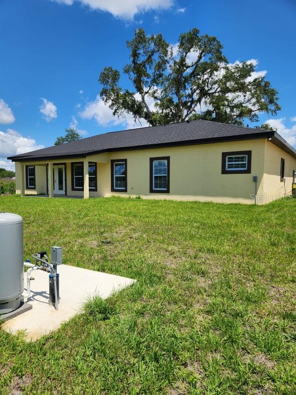 13074 SW 104th Ln, Dunnellon, FL 34432 - rear view of house featuring stucco siding and a yard