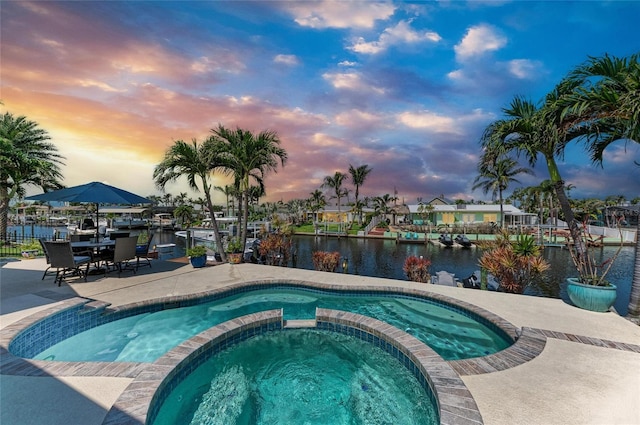 4508 Mangrove Point Rd, Bradenton, FL 34210 - pool at dusk with a water view, a pool with connected hot tub, and a patio