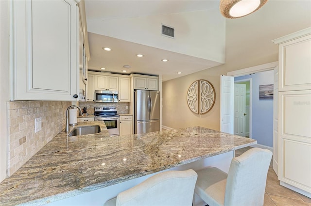 4508 Mangrove Point Rd, Bradenton, FL 34210 - kitchen featuring appliances with stainless steel finishes, a sink, backsplash, light stone countertops, and a peninsula
