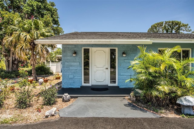 2216 Lake Shore Dr, Nokomis, FL 34275 - doorway to property featuring brick siding, covered porch, and roof with shingles