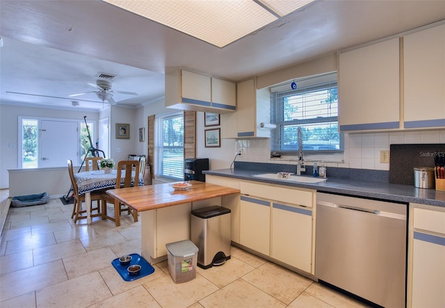 2216 Lake Shore Dr, Nokomis, FL 34275 - kitchen featuring stainless steel dishwasher, dark countertops, decorative backsplash, light tile patterned flooring, and ornamental molding