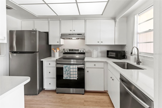 643 Park Cir, Bradenton, FL 34207 - kitchen with stainless steel appliances, extractor fan, white cabinets, and light wood-style floors