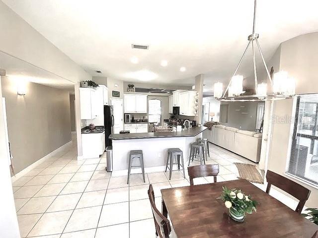 11315 Cypress Shore Ct, Clermont, FL 34711 - dining area with light tile patterned floors, a chandelier, and baseboards