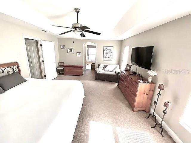 11315 Cypress Shore Ct, Clermont, FL 34711 - bedroom with arched walkways, multiple windows, light carpet, ceiling fan, and lofted ceiling