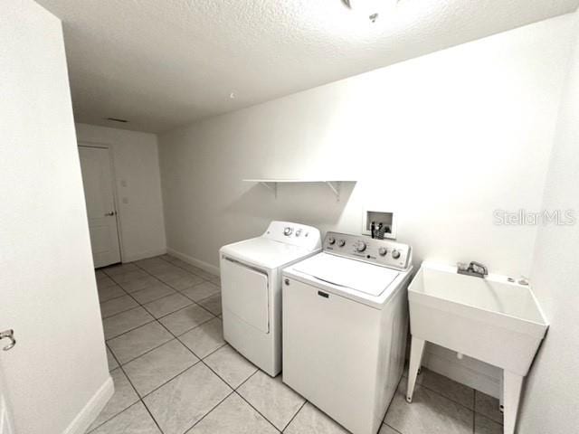 11315 Cypress Shore Ct, Clermont, FL 34711 - washroom featuring washing machine and clothes dryer, light tile patterned floors, baseboards, and a textured ceiling