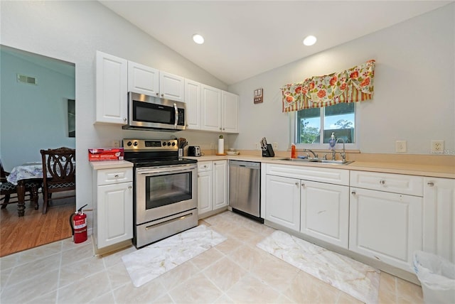 590 Ridgewood St NW, Port Charlotte, FL 33952 - kitchen featuring stainless steel appliances, a sink, lofted ceiling, white cabinets, and light countertops
