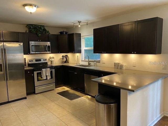 1616 NW 39th Ave, Gainesville, FL 32605 - kitchen featuring appliances with stainless steel finishes, a peninsula, tasteful backsplash, light tile patterned floors, and dark cabinetry