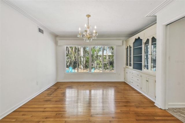 3001 Bay Shore Cir, Sarasota, FL 34234 - unfurnished dining area with crown molding, a chandelier, wood-type flooring, and baseboards